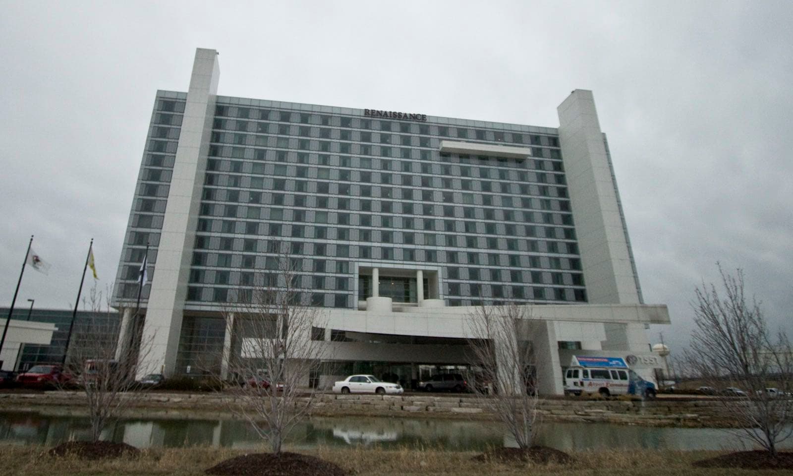 Renaissance Schaumburg Convention Center Hotelの客室棟を池越しに見上げた外観。曇天の下、正面に車寄せの庇があり、左奥にコンベンションセンター棟が続く