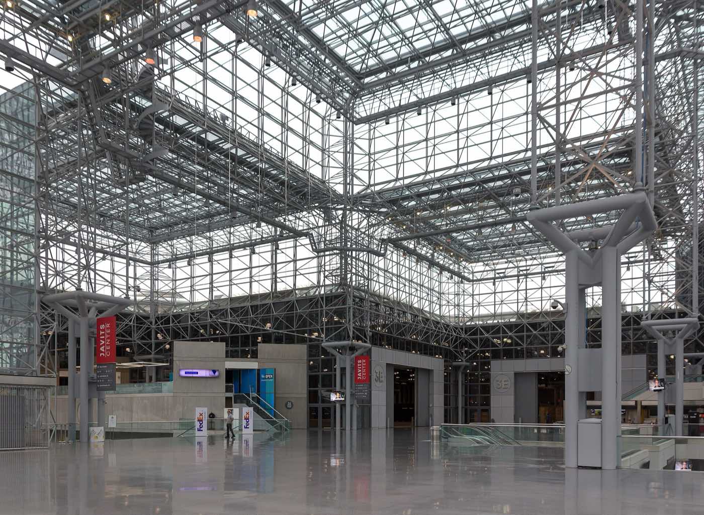 Javits Centerの屋内コンコース。鉄骨のスペースフレームとガラス天井の下に広い床が続き、奥に展示ホール3Eの入口が見える