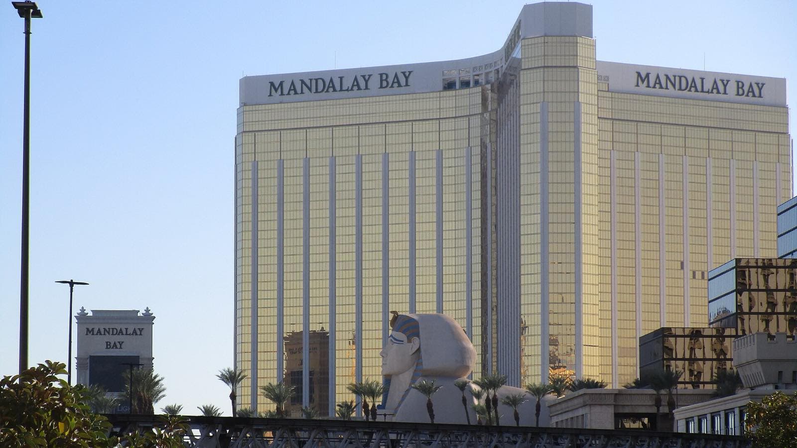 高架軌道の奥に、屋上へ「MANDALAY BAY」と大きく掲げた高層ホテルが2面見え、手前にはLuxorのスフィンクス像が立っている