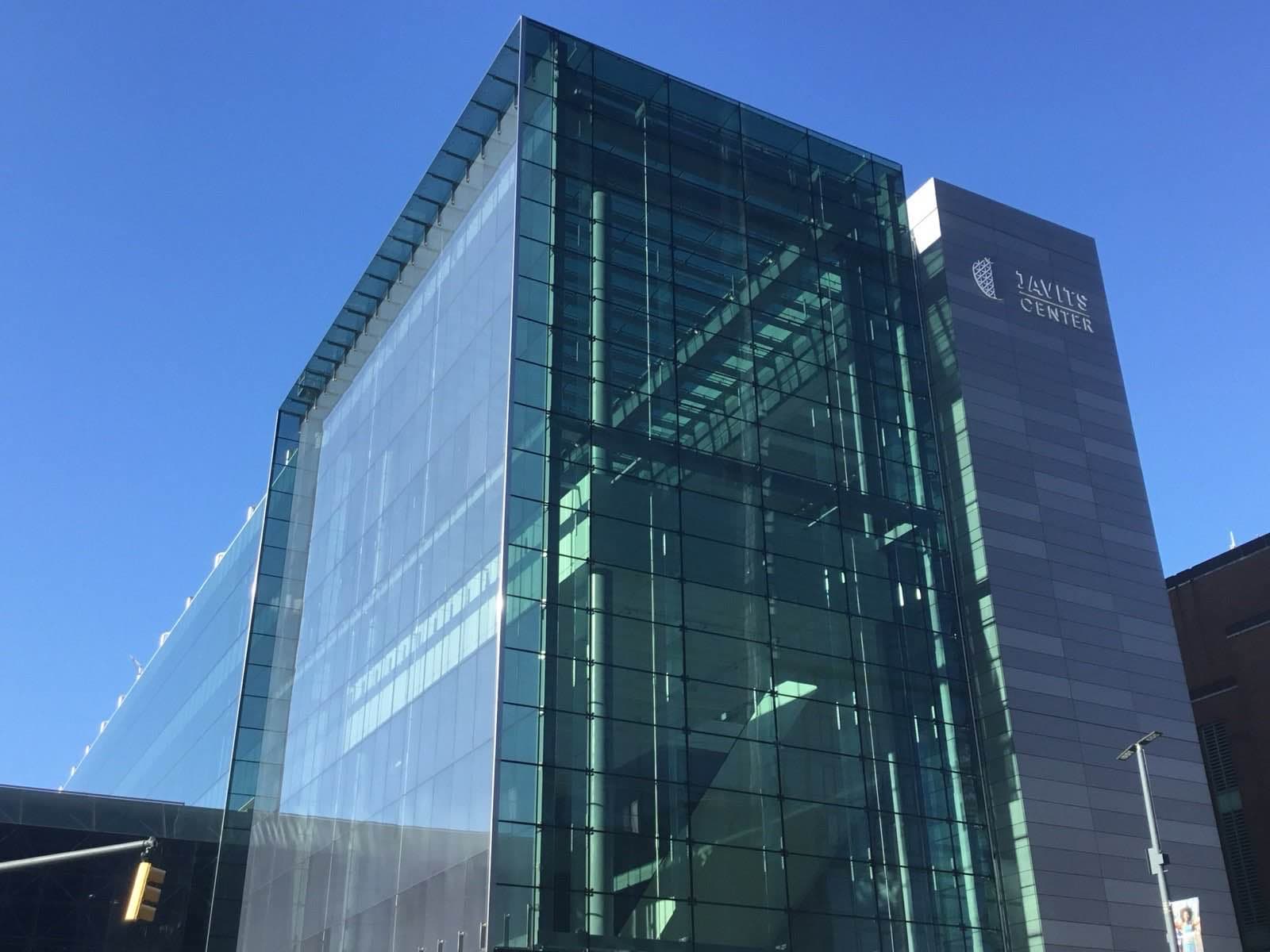 青空を背景にしたJavits Centerのガラス張りの外観。角に立つ高層部の壁面に施設名のサインが見える