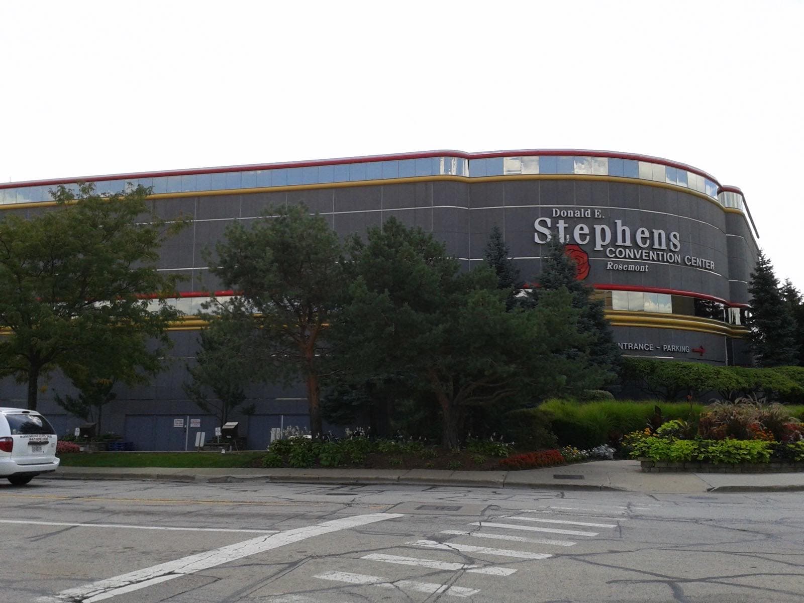 灰色の外壁に赤と金のラインが走る円弧状の建物と、Donald E. Stephens Convention Centerの文字看板