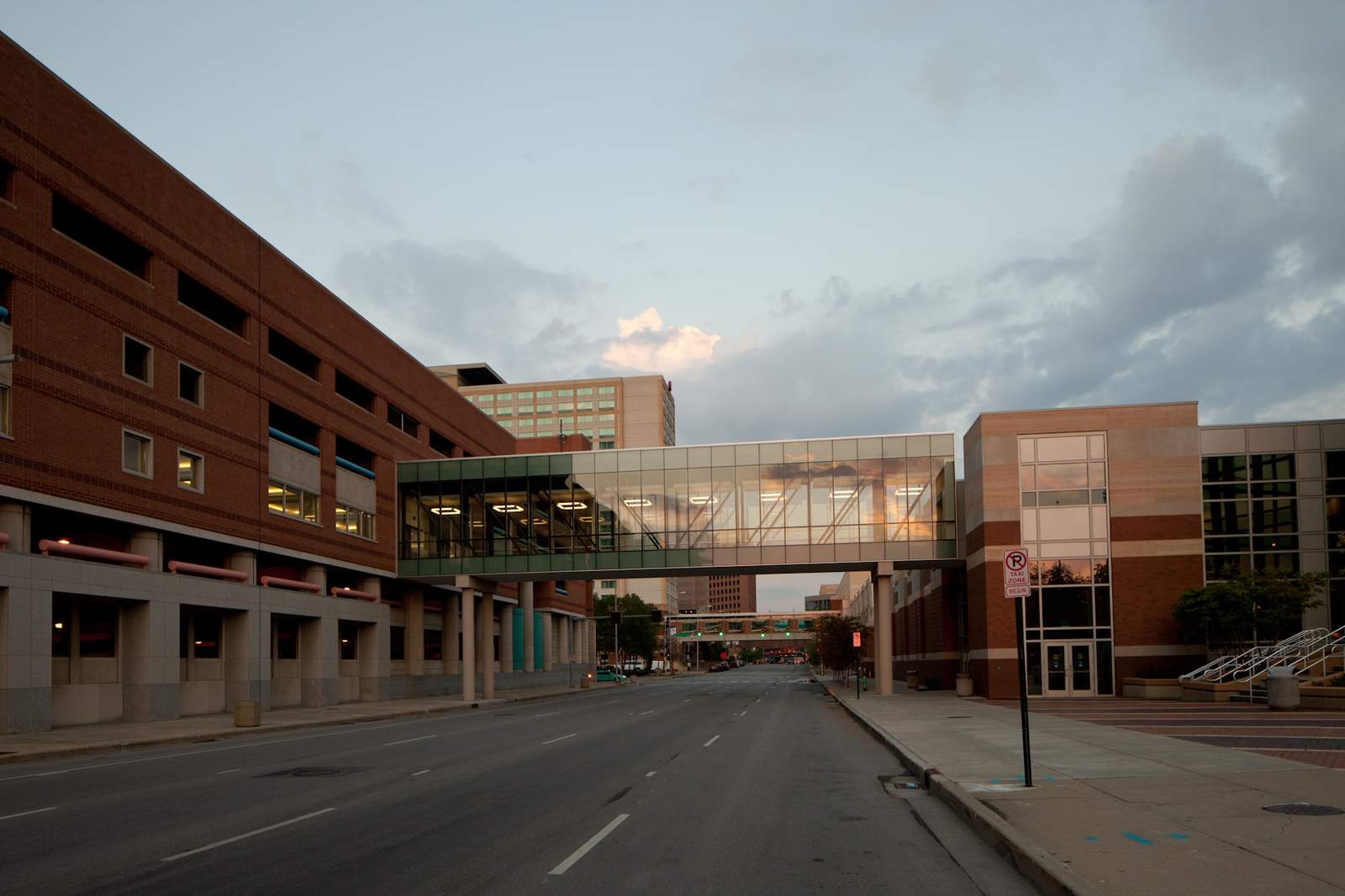 夕暮れの街路をまたいで、Indiana Convention Centerと駐車場ビルを結ぶガラス張りの空中連絡通路