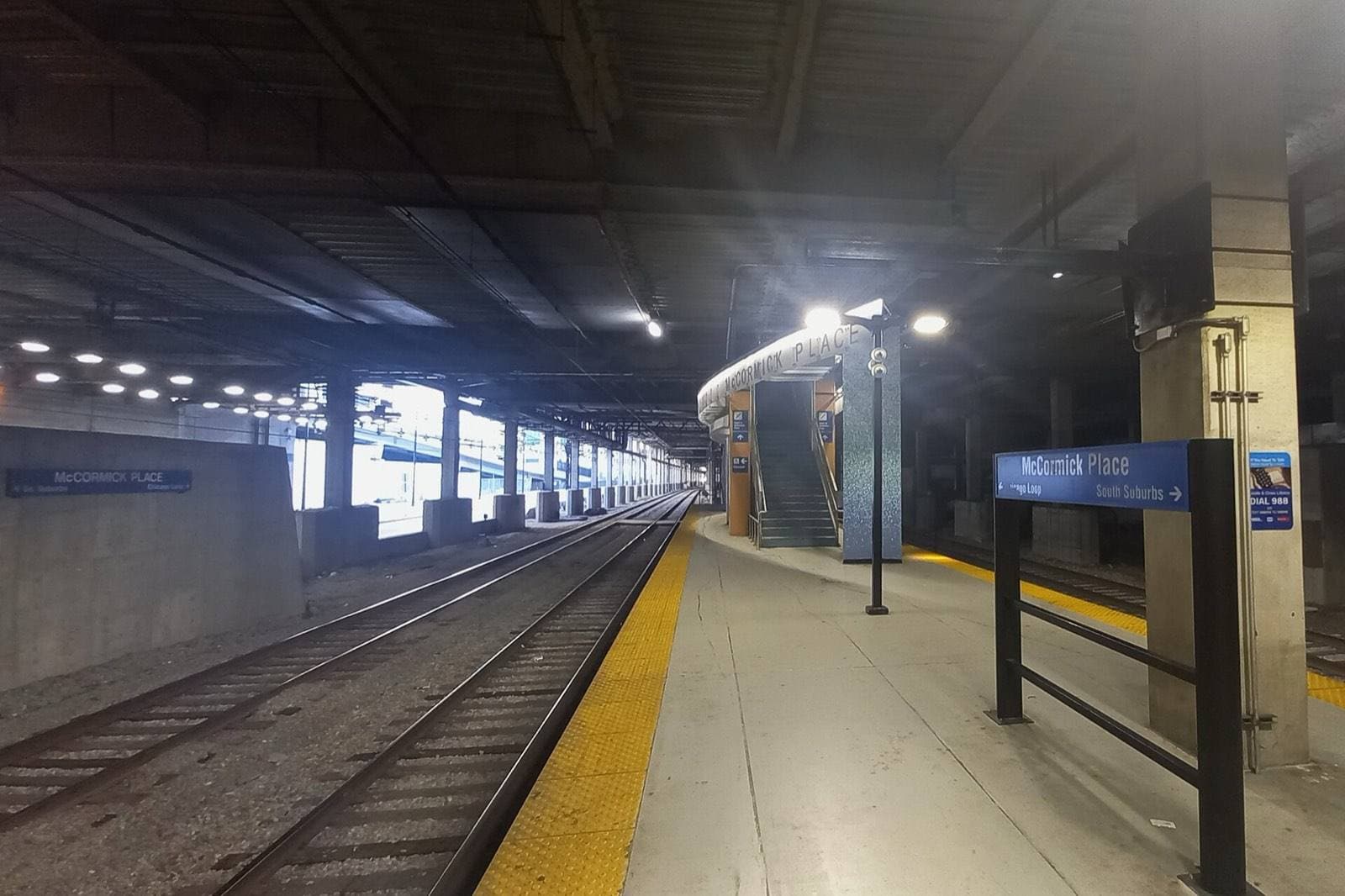 マコーミック・プレイス館内にある鉄道駅のホーム。線路の先に McCormick Place と書かれた案内標識と、上階へ向かう階段が見える