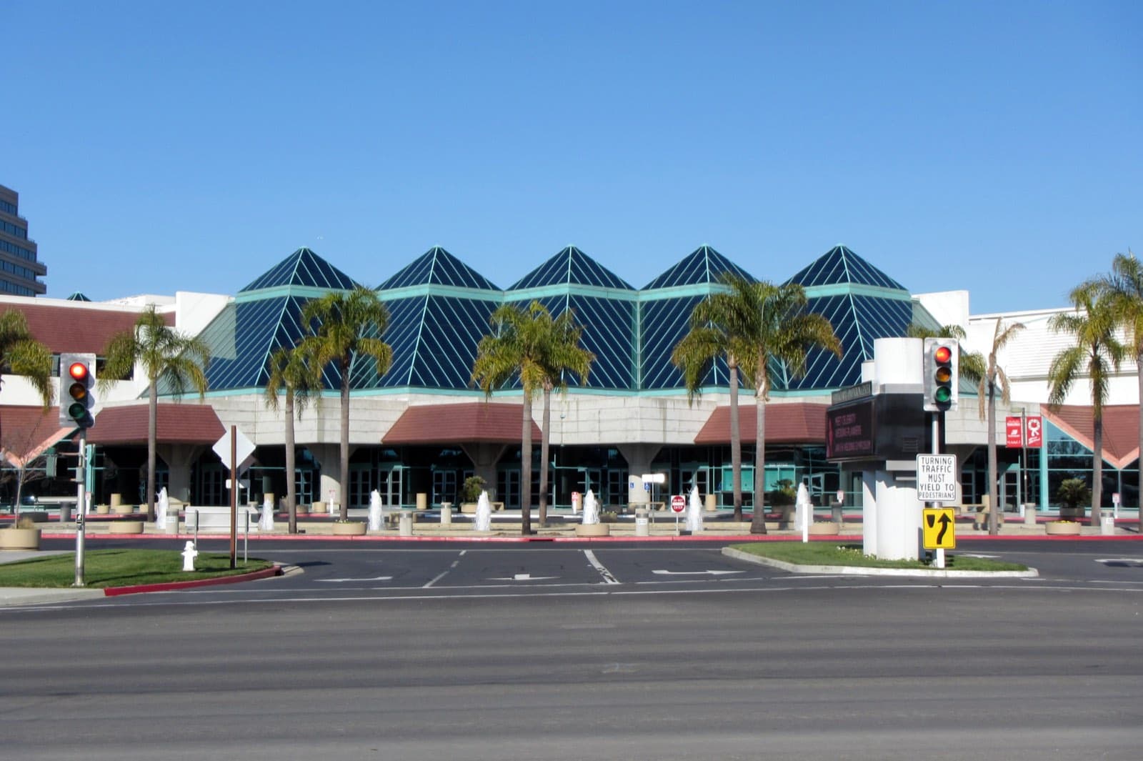 ピラミッド型の青いガラス屋根が並ぶSanta Clara Convention Centerの正面外観。手前にヤシの木と噴水