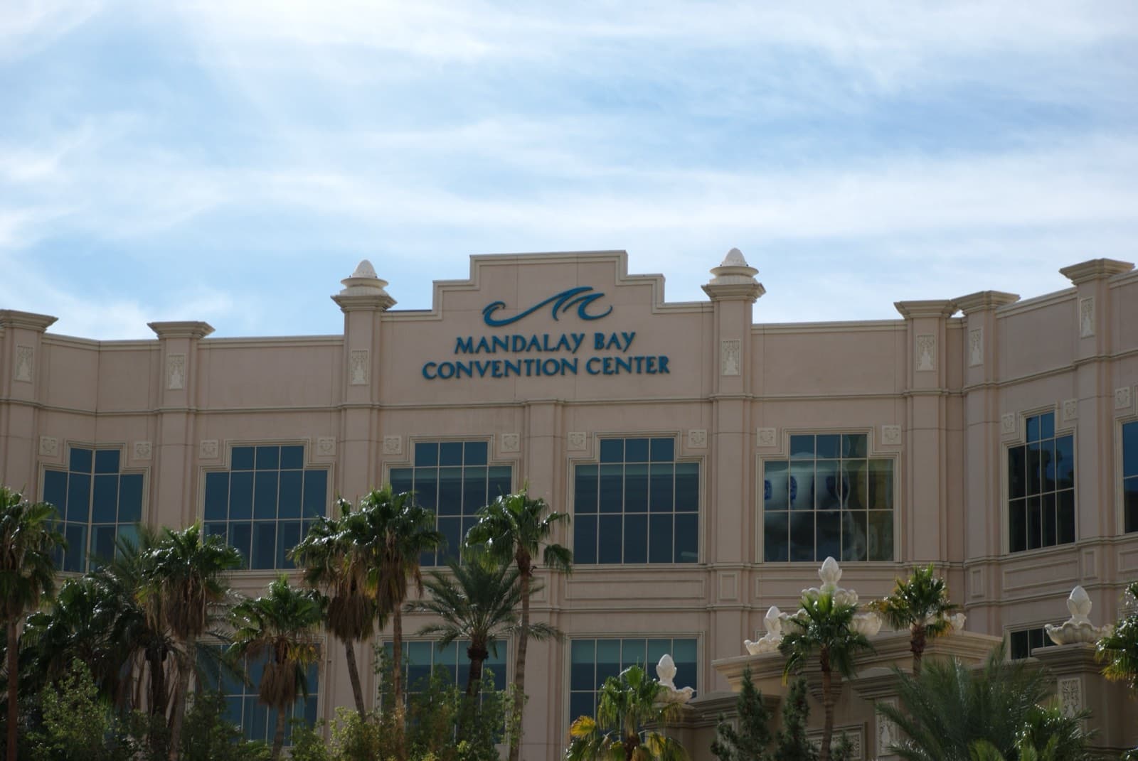 「MANDALAY BAY CONVENTION CENTER」と大きく掲げられた建物の外壁と、手前に並ぶヤシの木