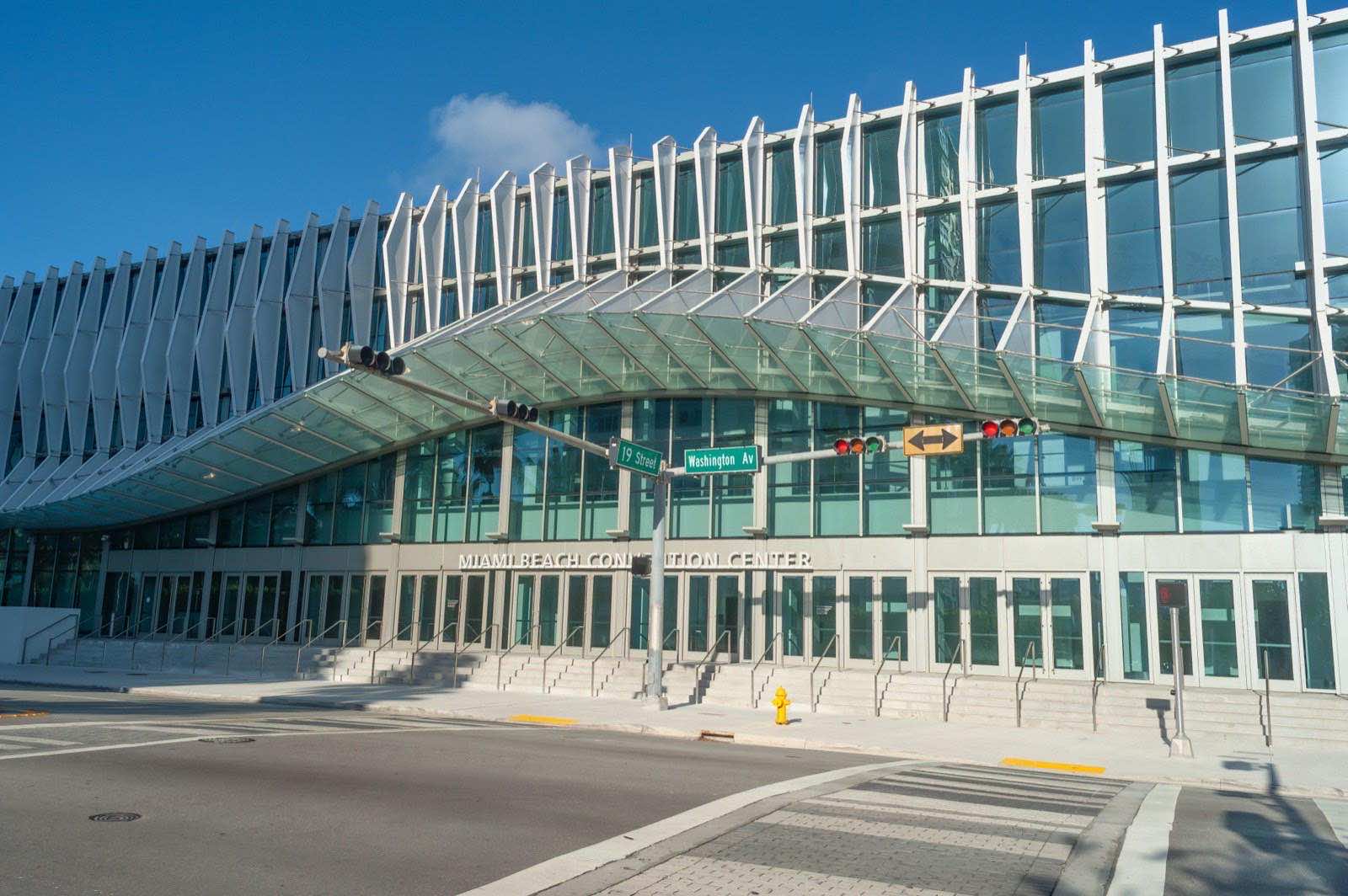 波打つ白いフィンとガラスで覆われたMiami Beach Convention Centerの外観。19 StreetとWashington Avenueの交差点から見た改修後の建物