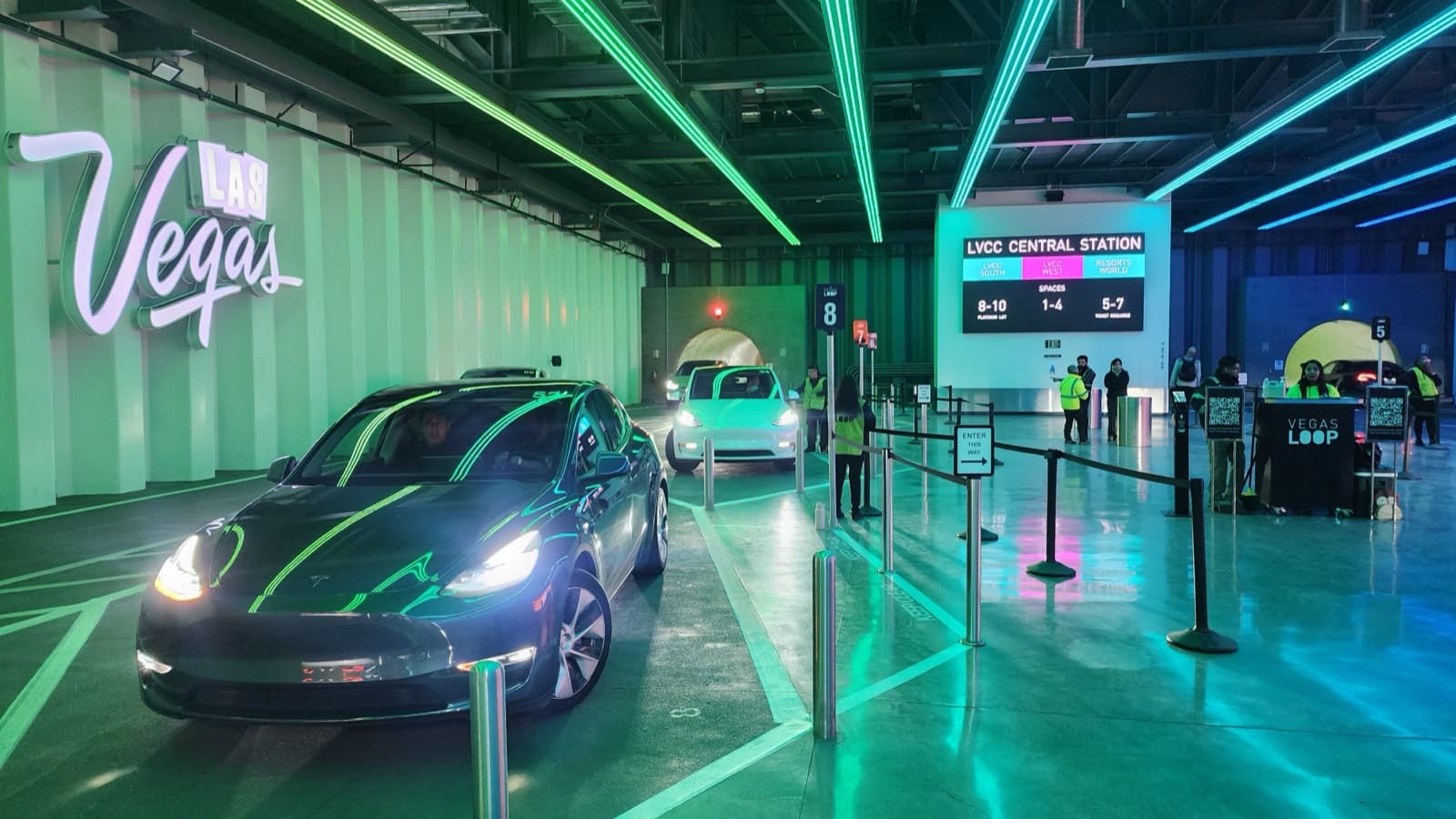 地下トンネルの乗り場に停まるテスラ車と、行き先を表示するLVCC Central Stationの電光掲示板