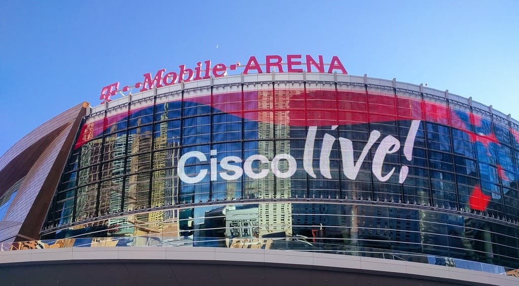 ラスベガスのT-Mobile Arenaの外観。曲面ガラスの壁面全体にCisco liveの大きなロゴが貼られ、上部にアリーナ名の赤いサインが見える