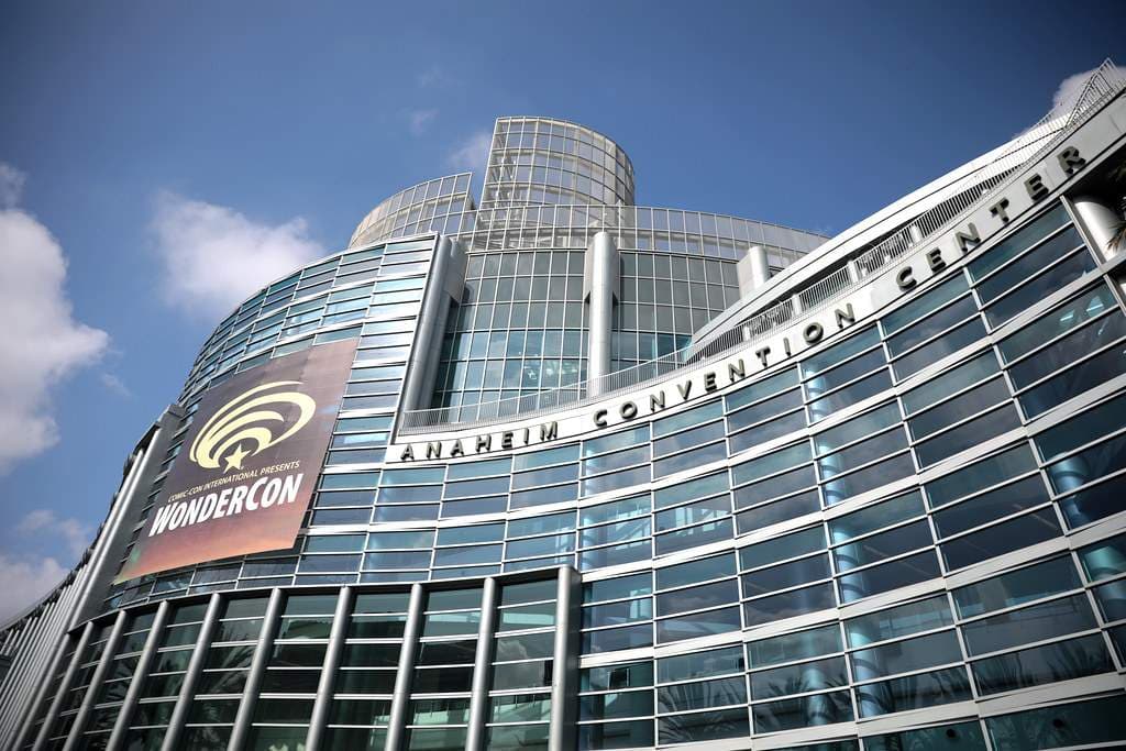 青空の下、ガラス張りの曲面外壁にANAHEIM CONVENTION CENTERの文字が並ぶ会議場を見上げた外観写真