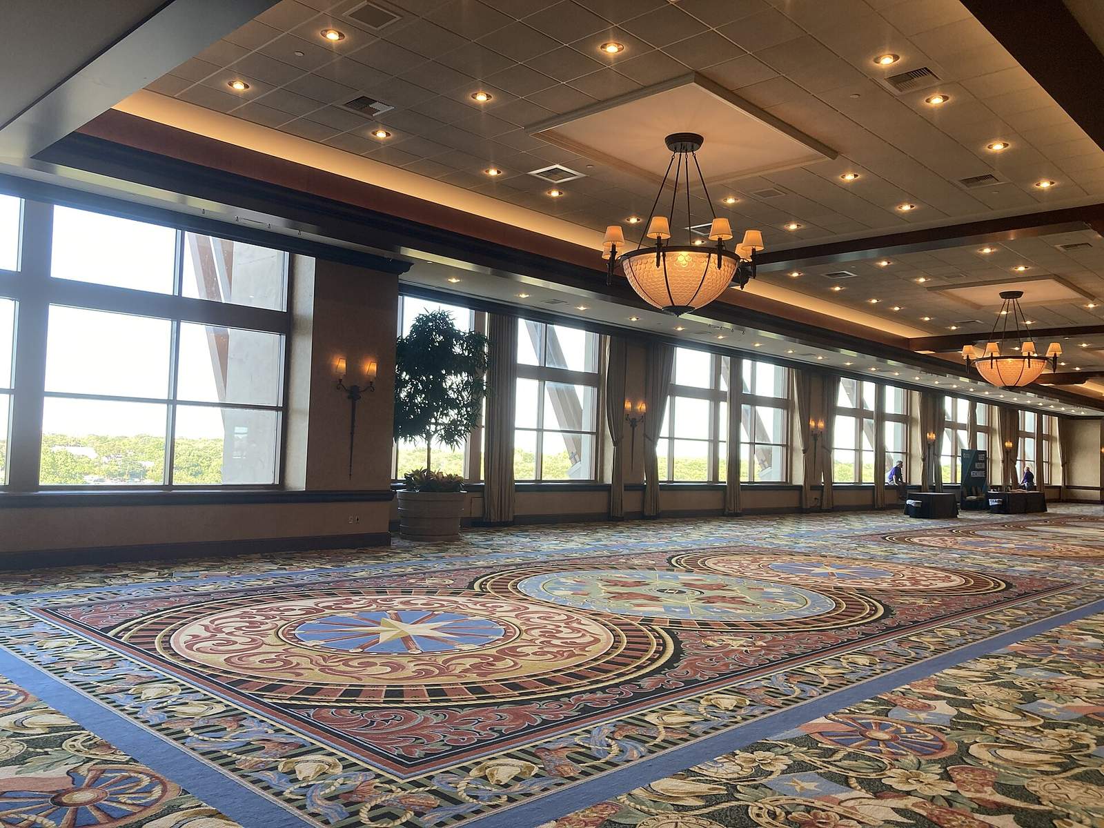 Gaylord Texanの会議場フロアのホワイエ。装飾的な絨毯が一面に敷かれ、シャンデリアが下がり、右奥へ続く窓の外にアトリウムのガラス屋根の白い骨組みが見える