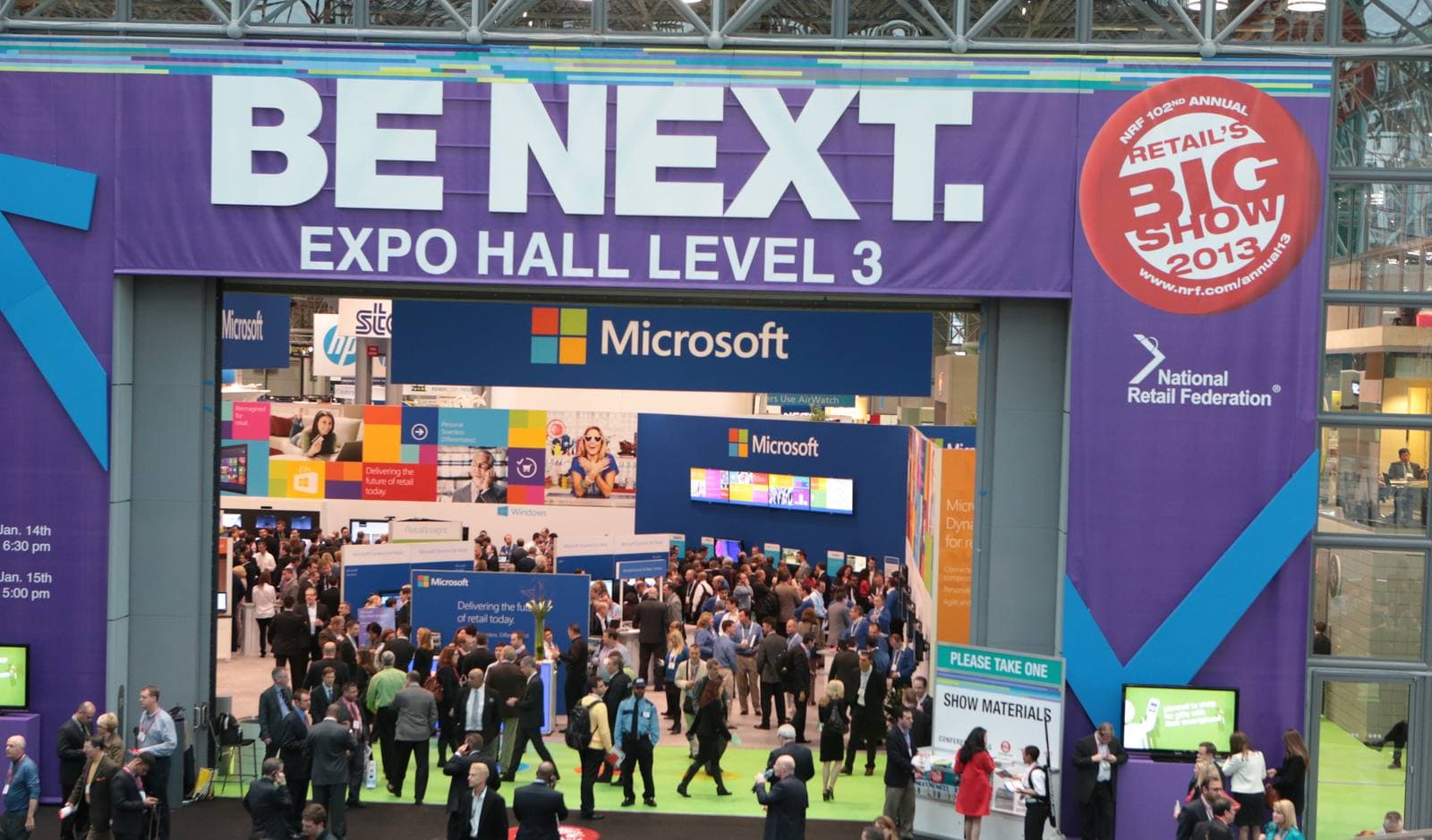 「BE NEXT. EXPO HALL LEVEL 3」と大書きされた紫の看板が掛かるExpoフロアの入口。看板の右端にはRetail's Big Showの円形ロゴがあり、入口の先では大勢の来場者が大型ブースのあいだを行き交っています