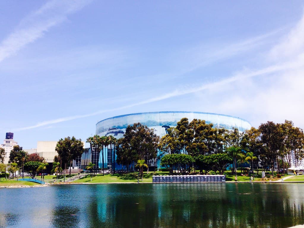 ヤシの木と池越しに見える、クジラの壁画が描かれたLong Beach Arenaの円形の建物