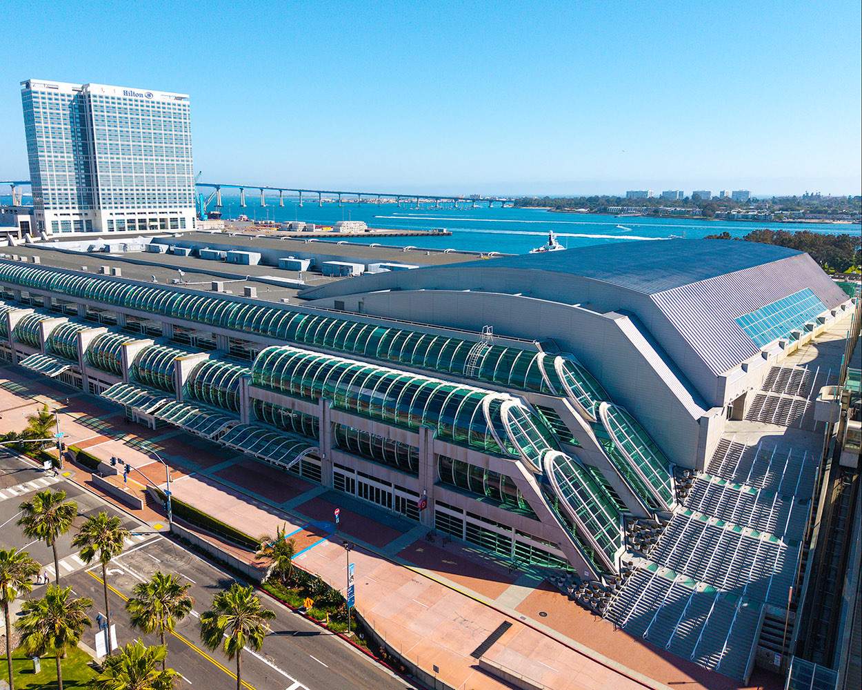 サンディエゴ湾に面したSan Diego Convention Centerを南西方向に見下ろした空撮。ガラスのかまぼこ屋根が連なり、左奥にヒルトン・サンディエゴ・ベイフロントの高層棟が建つ
